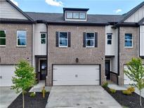 Charming townhome exterior featuring a brick facade, attached garage, and well-manicured landscaping at 5702 Urban Village Way # 2, Tucker, GA 30084