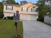 Charming split-level home features a two-car garage, dark shutters, and inviting front yard at 2880 Field Spring Dr, Lithonia, GA 30058