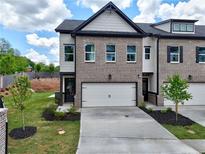 Beautiful townhome featuring a brick facade, attached garage, and landscaped front yard at 5700 Urban Village Way # 1, Tucker, GA 30084