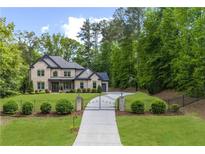 Stunning two-story brick home with manicured lawn and gated driveway entrance at 885 Old Peachtree Ne Rd, Lawrenceville, GA 30043