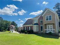 Charming two-story home with a well-manicured lawn, brick accents, and lush landscaping on a sunny day at 479 Rising Sun Path, Lawrenceville, GA 30043