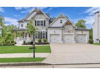 Beautiful two-story home with stone accents, a three-car garage, and manicured front yard at 6150 Bridge Fair Rd, Cumming, GA 30028