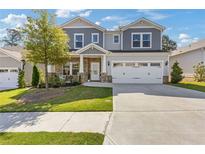 Charming two-story home featuring a stone-accented facade, manicured lawn, and a spacious two-car garage at 704 Chipping Sparrow St, Canton, GA 30115