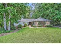 Charming single-story home featuring a well-manicured lawn and a stone facade, surrounded by mature trees at 125 Fortuna Ct, Roswell, GA 30075