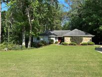 Charming home with a well-manicured front yard, mature trees, and stone accents, creating a welcoming curb appeal at 125 Fortuna Ct, Roswell, GA 30075
