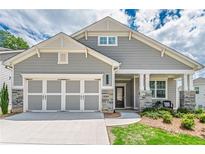 Charming home featuring stone accents, gray siding, a two-car garage, and manicured landscaping at 213 Hickory Bluffs Pkwy, Canton, GA 30114