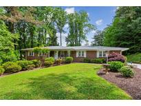 Charming brick home with manicured lawn, lush landscaping, and mature trees at 261 Demetra Se Dr, Mableton, GA 30126