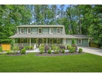 Charming two-story home features a lush green lawn and inviting front porch perfect for relaxing and enjoying the outdoors at 220 Hillswick Ct, Atlanta, GA 30328