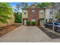 Charming townhome featuring brick and siding facade, driveway, and well-maintained landscaping at 3037 Bonnes Dr, Lithonia, GA 30038