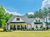 Beautiful two-story farmhouse with a well-manicured lawn and a charming front porch at 62 Presley Farm Pkwy, Rockmart, GA 30153