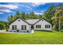 Charming painted brick home featuring black shutters, a new roof, and a well-manicured lawn and landscaping at 2334 Fisher Dr, Loganville, GA 30052