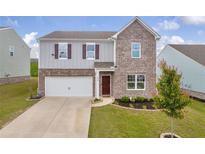Two story home featuring a brick and gray facade, attached garage, and a well manicured lawn at 3828 Ramsay Pass, Loganville, GA 30052