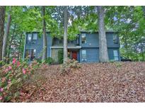 Inviting two-story home with beautiful landscaping and a charming red front door nestled among mature trees at 3067 Nuptial Ln, Lawrenceville, GA 30044