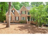 Charming two-story red brick home with manicured lawn and mature trees in a well-maintained neighborhood at 5065 Hickory Hills Dr, Woodstock, GA 30188