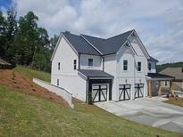 New construction two-story home with white siding, black roof, and three-car garage at 222 Silvercrest Dr, Acworth, GA 30101