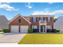 Charming two-story brick home with a well-manicured lawn, two-car garage, and inviting front porch at 310 Hammersmith Dr, Suwanee, GA 30024