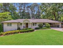 Charming one-story home features a lush green lawn, tidy landscaping, and a convenient carport at 305 Montevallo Dr, Atlanta, GA 30342