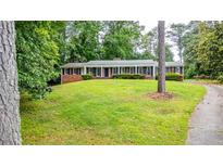 A sprawling front yard leads up to a brick home with a long, covered front porch at 3916 Ridgewood Se Dr, Smyrna, GA 30080