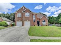 Charming two-story brick home with a well-manicured lawn and a long driveway leading to a two-car garage at 2678 Adair Trl, Dacula, GA 30019