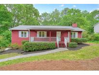 Charming red home with white trim, a cozy front porch, and well-maintained landscaping at 2900 Country Nw Ct, Kennesaw, GA 30152