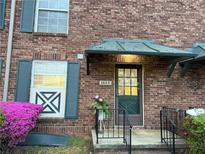 Charming brick home featuring an inviting entrance with green door and lush flowering plants at 5685 Kingsport Dr, Sandy Springs, GA 30342