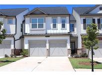 Charming townhome with a two-car garage, a well-manicured lawn, and gray and white accents at 5790 Thornton Dr, Cumming, GA 30028
