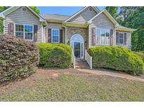Charming front exterior with stone accents, a well-manicured lawn, and lush landscaping at 6790 India Ln, Cumming, GA 30041