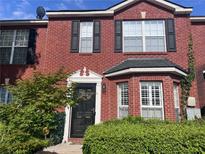 Charming two-story brick townhouse with black shutters, decorative door, and well-maintained landscaping at 5536 Strathmoor Manor Cir, Lithonia, GA 30058
