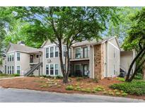 Attractive condo building with beige siding, stone accents, balconies, and lush landscaping at 1214 Lake Pointe Cir, Roswell, GA 30075