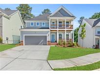 Charming two-story home featuring a covered porch, balcony, well-maintained lawn, and attached two-car garage at 411 Riverclub Rd, Acworth, GA 30101