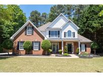 Charming two-story home with a manicured lawn, brick facade, black shutters, and inviting front porch at 2735 Princeton Trce, Cumming, GA 30041