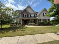 Inviting two-story home featuring stone accents, a well-manicured lawn, and a charming covered front porch at 4316 Kershaw Dr, Snellville, GA 30039