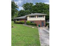 Split-level home with brick and siding, green lawn and mature trees at 2433 Tilson Rd, Decatur, GA 30032