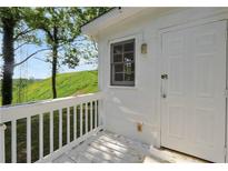 Side view of white house with a white railing and a door, against the backdrop of a grassy hill at 4682 Stonewall Tell Rd, College Park, GA 30349