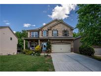 Charming two-story brick home featuring a front porch, attached garage, and a well-manicured lawn at 5655 Hedge Brook Dr, Cumming, GA 30028