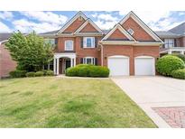 Traditional brick home with a two-car garage, manicured lawn, and mature landscaping at 2310 Norbury Se Cv, Smyrna, GA 30080