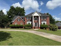 Traditional red brick home with large columns and a well-manicured front lawn under a bright sky at 1301 Winesap Se Ct, Conyers, GA 30013