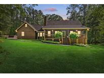 Inviting home featuring a well-manicured lawn and covered front porch nestled in mature trees at 4615 Gresham Rd, Douglasville, GA 30134