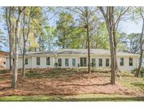 Inviting one-story home featuring a light brick facade, complemented by mature trees, and an open yard at 2729 Ridge Valley Nw Rd, Atlanta, GA 30327