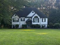 Charming two-story home featuring well-manicured lawn, black accents, and lush landscaping at 5022 Cliff Top Dr, Loganville, GA 30052