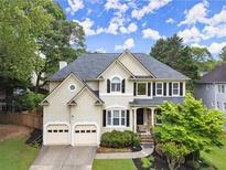 Charming two-story home featuring a two-car garage, manicured lawn, and beautiful landscaping at 6790 Wolford Ct, Johns Creek, GA 30097