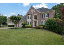 Beautiful brick home featuring a lush green lawn, mature trees, and a meticulously landscaped front yard at 3143 Denton Ne Pl, Roswell, GA 30075