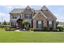 Charming two-story home with stone and brick facade, landscaped front yard, and decorative shutters at 320 Harvest View Ter, Woodstock, GA 30188