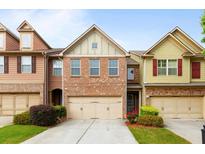 Charming brick townhome featuring a two-car garage and manicured front lawn at 1539 Creek Bend Ln, Lawrenceville, GA 30043