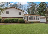 Two-story home featuring light siding, an attached garage, manicured lawn, and mature trees at 2325 Lago Dr, Jonesboro, GA 30236