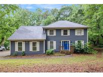 Charming two-story home with blue siding, white trim, bright blue front door, and mature trees at 295 N Fayette Dr, Fayetteville, GA 30214