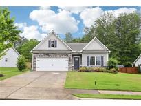Charming single-Gathering home with stone accents, a well-manicured lawn, and a two-car garage at 306 Lark Ln, Canton, GA 30115