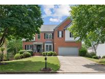 Charming two-story brick home featuring a well-maintained lawn and a two-car garage at 11040 Regal Forest Dr, Johns Creek, GA 30024