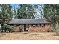 Charming brick home with a dark roof surrounded by mature trees in a suburban neighborhood at 1491 Boulderwoods Dr, Atlanta, GA 30316