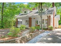Charming two-story home with white siding, brick accents, front porch, dormer windows, and landscaped front yard at 291 Elmira Ne Pl, Atlanta, GA 30307